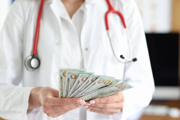 Doutor detém notas de dólar em dinheiro em suas mãos — Fotografia de Stock