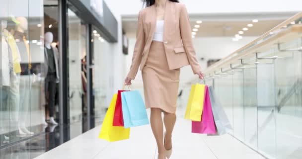 Jeune femme marchant à travers le centre commercial avec de nombreux paquets dans ses mains film 4k — Video