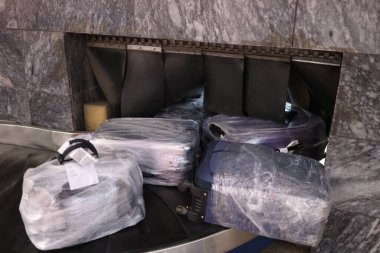 Koruyucu filmdeki bavullar nakliye bandında.