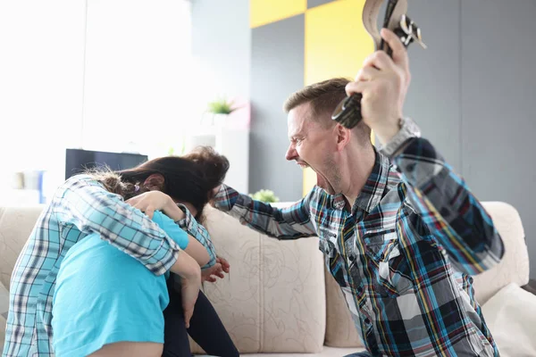 Злой мужчина кричит на жену и ребенка, держащих ремень в руке — стоковое фото