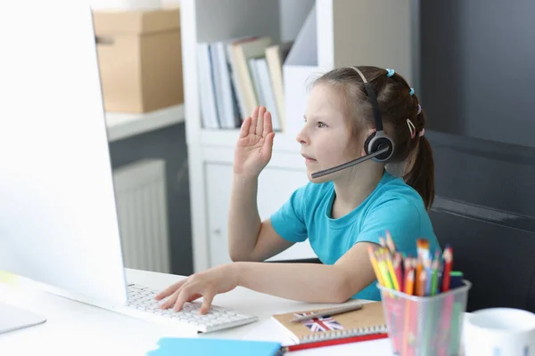 Chica en auriculares se sienta en el monitor de la computadora y estira los brazos para responder en línea lesso —  Fotos de Stock