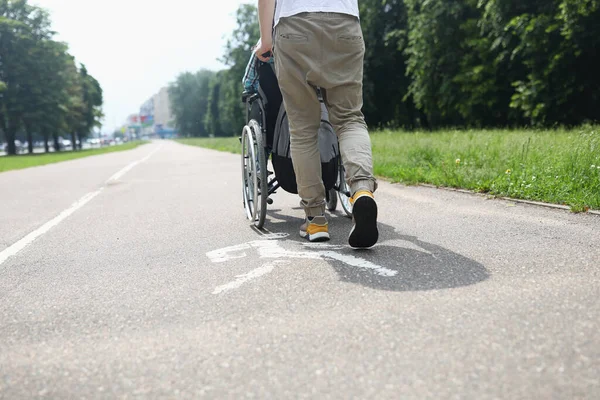 Man hjälper handikappade i rullstol att gå på trottoaren — Stockfoto