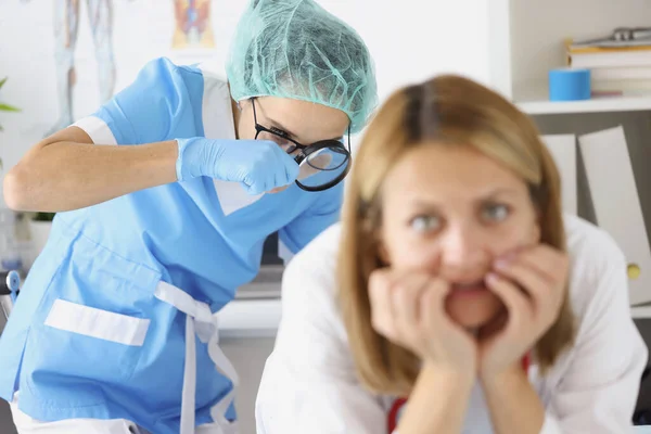 Врач осматривает женскую прямую кишку увеличительным стеклом в клинике — стоковое фото