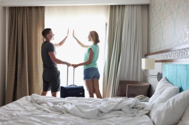 Bavullu genç erkek ve kadınlar otel odasında beş el uzatıyorlar.