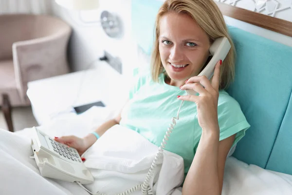 Jovem deitada na cama e conversando ao telefone em casa — Fotografia de Stock