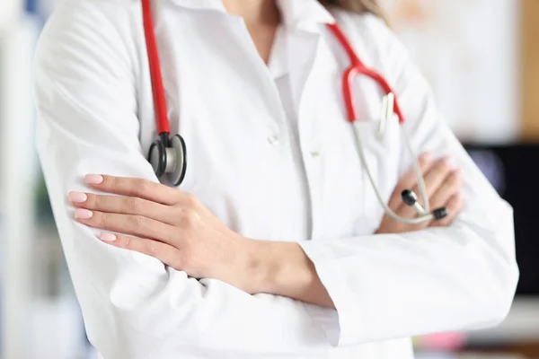 Női orvos fehér köpenyben és sztetoszkóp áll összecsukott karokkal — Stock Fotó