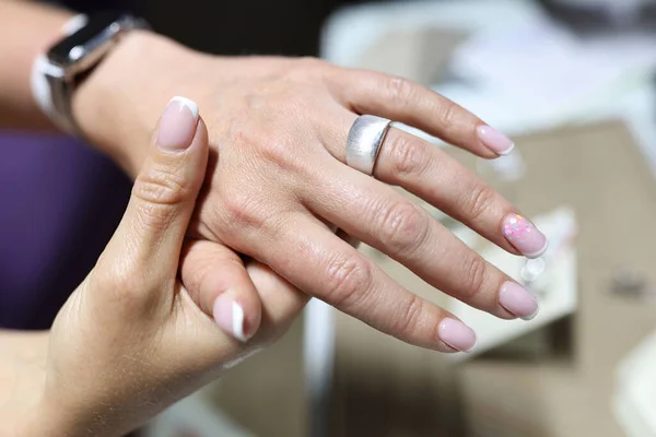 Женщина примеряет широкое серебряное кольцо на пальце — стоковое фото