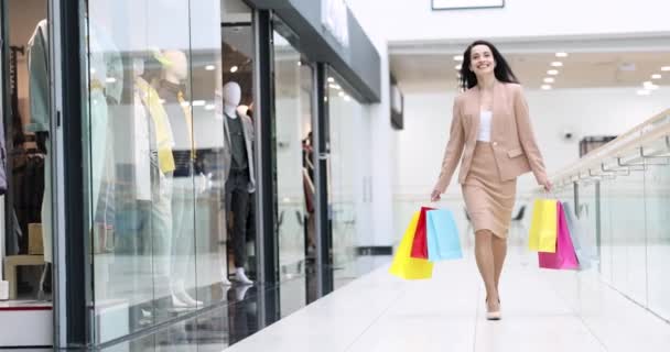 Heureuse femme souriante marchant dans le centre commercial avec de nombreux sacs multicolores dans ses mains film 4k — Video