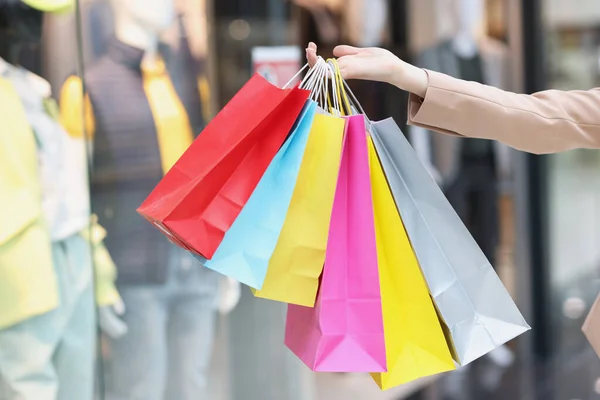 Sacos de papel multicoloridos em mãos femininas no fundo do shopping — Fotografia de Stock