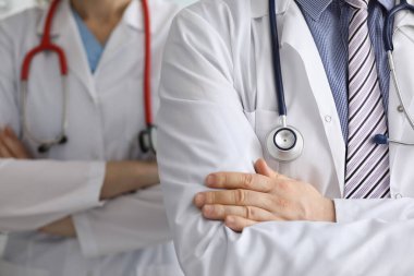 Boyunlarında steteskop olan doktorlar kollarını kavuşturup yakın plan çekiyorlar.