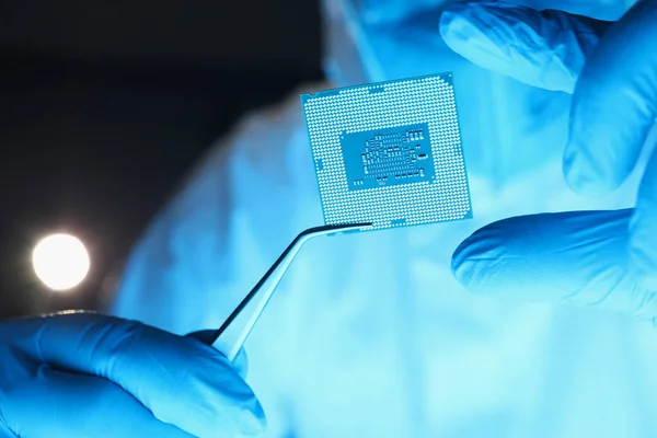 Reparador sosteniendo procesador de computadora con pinzas en primer plano de laboratorio — Foto de Stock