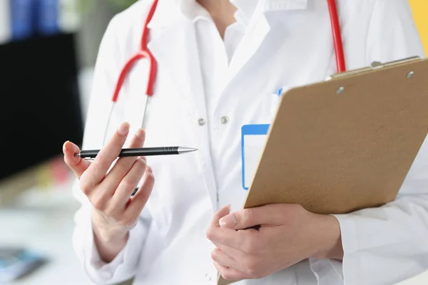 Doktorn håller urklipp med dokument och kulspetspenna i händerna närbild — Stockfoto