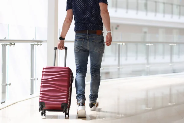 Man is rolling suitcase in hotel corridor — Stock Photo, Image