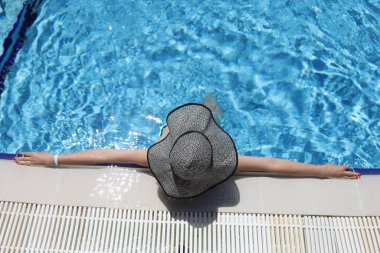 Panama 'lı kadın havuzda yatıyor, kolları açık, yukarıdan bakıyor.