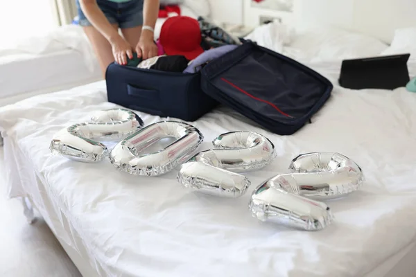 Срібні кулі з номерами 2022 лежать на ліжку з валізою в спальні крупним планом — стокове фото