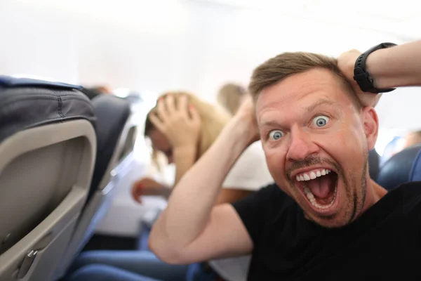 Erkek yolcu başını tutuyor ve uçakta bağırıyor. — Stok fotoğraf