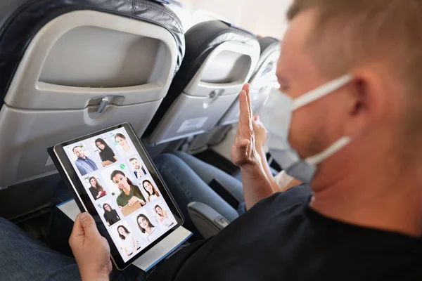 El hombre con máscara médica protectora lleva a cabo una conferencia en línea de negocios remotos a través de tabletas mientras está en transporte — Foto de Stock