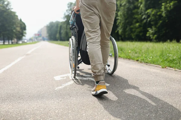 Man rullande rullstol med funktionshindrade person på trottoaren närbild — Stockfoto