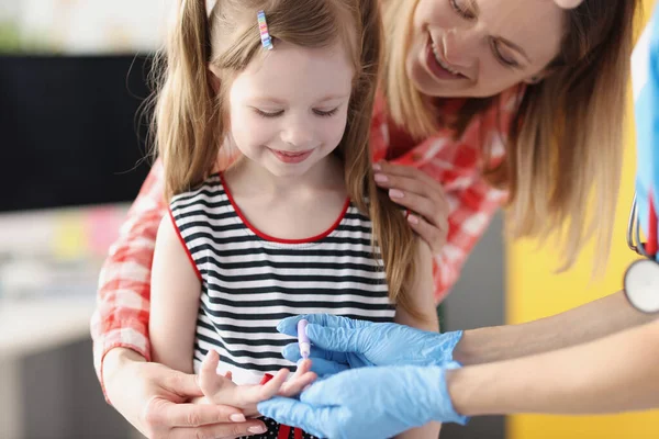 Доктор лабораторії асистент приймати кров маленької дівчинки, використовуючи ланцет в клініці — стокове фото