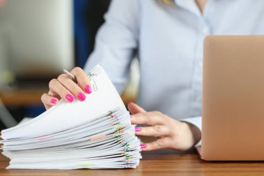 Ofiste elinde renkli ataçlarla bir sürü belge tutan bir kadın.