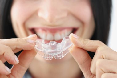 Gülümseyen kadın diş beyazlatmak için plastik ağız koruyucusu tutuyor.
