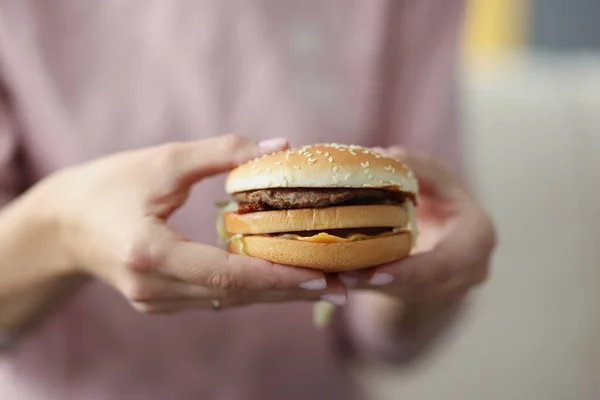 Vrouw met heerlijke smakelijke hamburger in haar handen closeup — Stockfoto