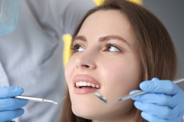 Doktor kadın hastaya diş muayenesi yapıyor.