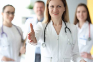 Beyaz önlüklü, gülümseyen ve ellerini uzatan doktorlardan oluşan bir ekip.