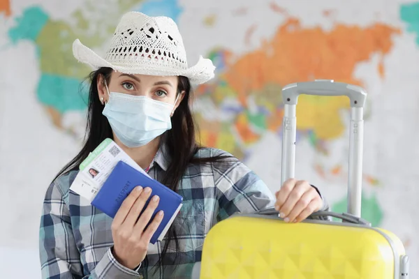 Woman tourist in medical protective mask and suitcase holds passport and certificate of vaccination against coronavirus infection — Stock Photo, Image