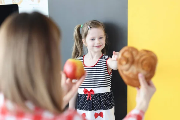 Mãe oferecendo pão ou maçã vermelha para a menina — Fotografia de Stock