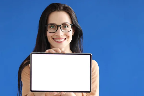 Giovane donna in occhiali che tiene tablet digitale con schermo bianco nelle sue mani — Foto Stock