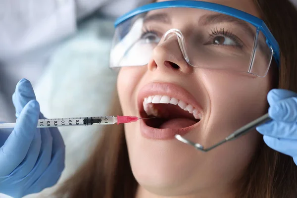 Врач-стоматолог делает инъекцию с анестезией в десну пациентки крупным планом — стоковое фото