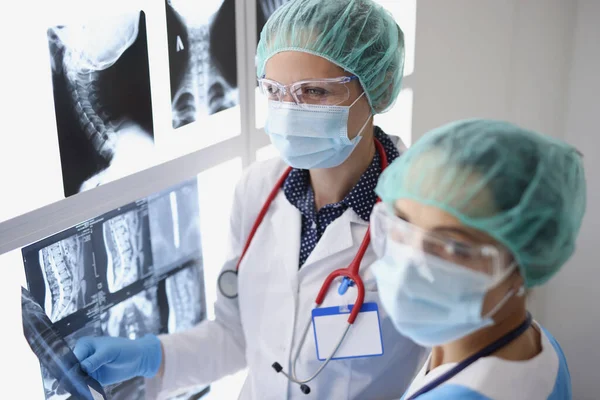 Dos doctores con máscaras protectoras médicas examinando rayos X médicos —  Fotos de Stock