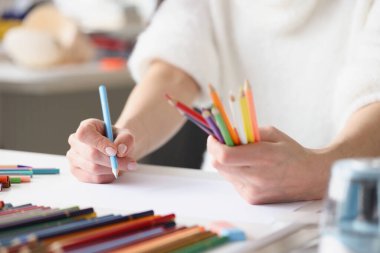 Beyaz kağıt üzerine çok renkli kalemler çizen kadın.