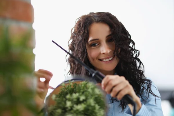 Young brunette woman winding her hair with curling iron at home — Stock Photo, Image