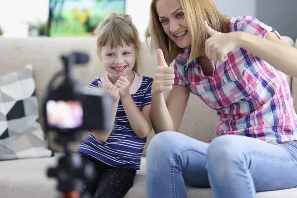 Mujer y niña mostrando el pulgar hacia arriba delante de la cámara en casa — Foto de Stock