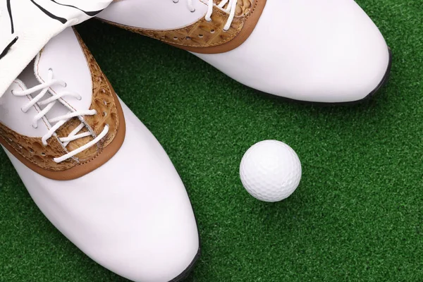 Chaussures blanches et balle couchée sur le terrain de golf vert gros plan — Photo