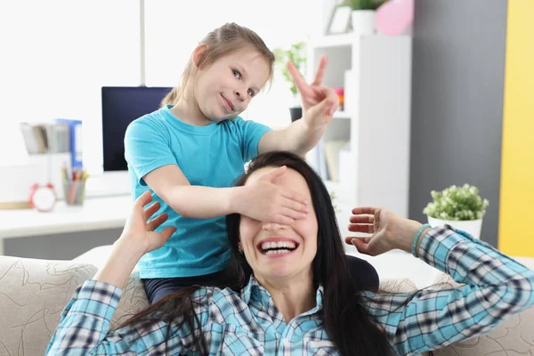 Kleines Mädchen schließt die Augen der lächelnden Mutter zu Hause — Stockfoto