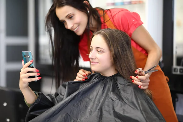 Kuaförlü genç bir kadın güzellik salonunda oturuyor ve akıllı telefondan selfie çekiyor. — Stok fotoğraf