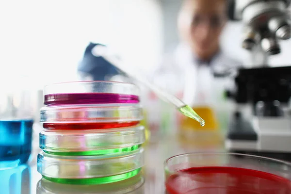 Artículos de vidrio de laboratorio con soluciones de diferentes colores en la mesa — Foto de Stock