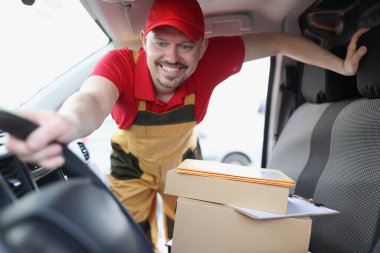 Kurye şoförü arabadaki karton kutuları alıyor.