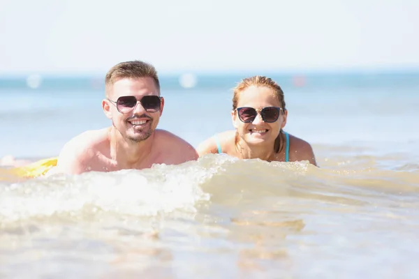 Giovane felice bella coppia donna e uomo sdraiato in acqua di mare — Foto Stock