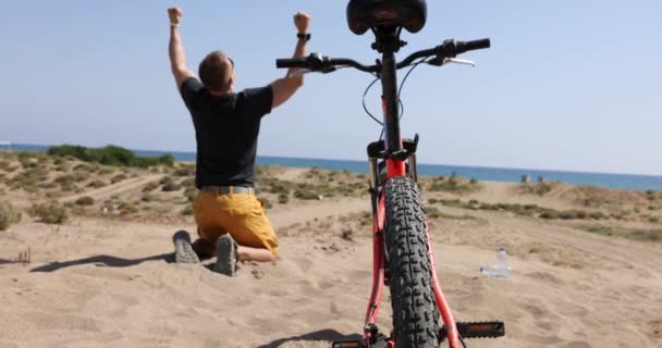 Man fietser verheugen en schreeuwen op de kust 4k film — Stockvideo