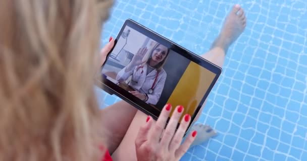 妇女坐在游泳池里，通过笔记本电脑屏幕与医生交流4k电影 — 图库视频影像