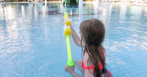 Kislány lövöldözés vízipisztoly medencében 4K film — Stock videók
