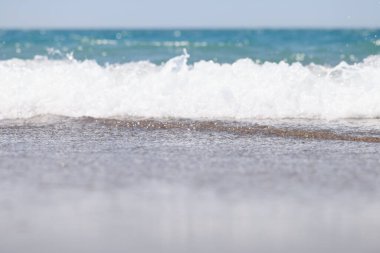 Büyük ve güçlü bir turkuaz fırtına dalgası. Beyaz köpük akıntıları ve kıyıda kırıklarla karışıyor.
