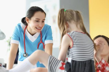Klinikteki randevusunda küçük kızı muayene eden kadın doktor.