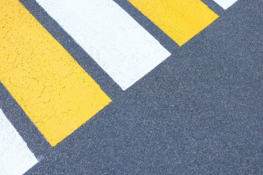 Yaya geçidinin sarı ve beyaz çizgileri asfalt zemin üzerine boyanmıştır.