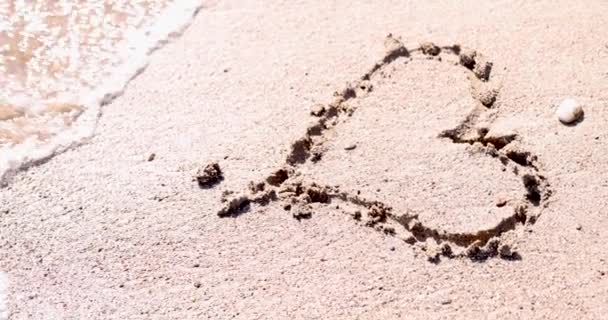 Gezeichnetes Herz am Strand Sand wurde von Welle aus Meer gespült 4k Film — Stockvideo