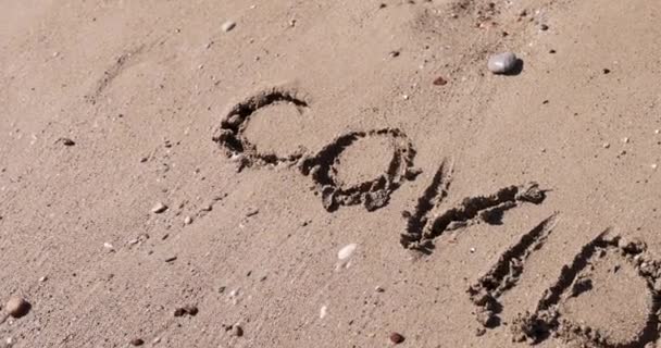 Covid belettering is geschilderd op strand zand 4k film — Stockvideo